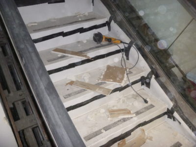 Escalator Step Covers in use at LAX to Protect Existing Escalator T1-1. Shows construction tools, and debris. Escalator unscathed as it is securely sealed via patented Escalator Step Covers by Hartman Products.